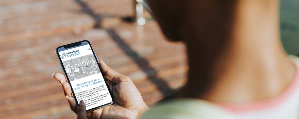 Image looking over a person's shoulder looking at client's website on a mobile phone