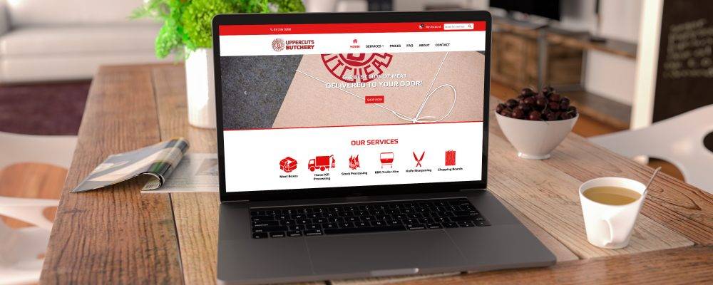 Uppercuts butchery website design by back9 creative displayed on a laptop on a rustic dining table
