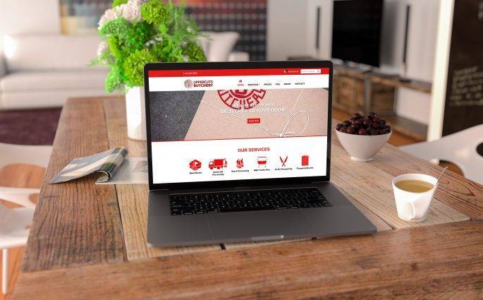 Uppercuts butchery website design by back9 creative displayed on a laptop on a rustic dining table